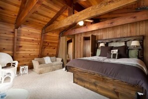Cozy cabin-style bedroom with a large bed, bedside lamps, and a comfortable sofa.