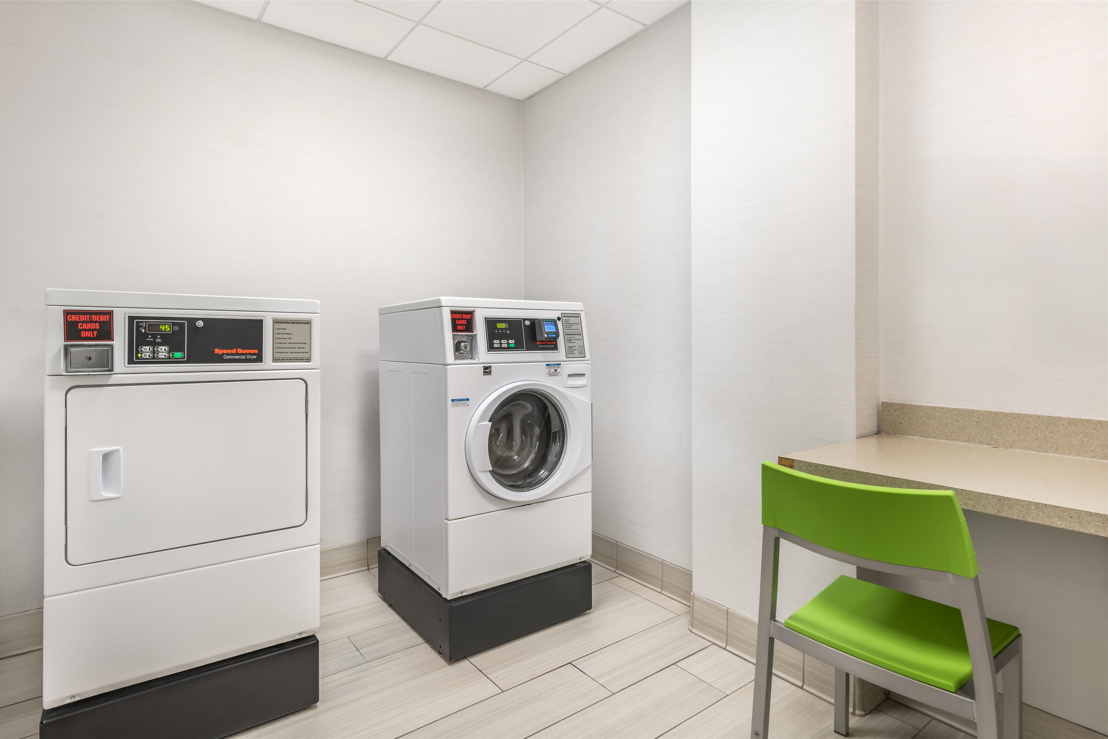 A laundry room with two washing machines and a chair.