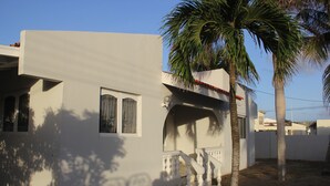 A modern house with a white exterior, a balcony, and a palm tree. - Fitz Aruba 2 Bedroom Home (Noord)