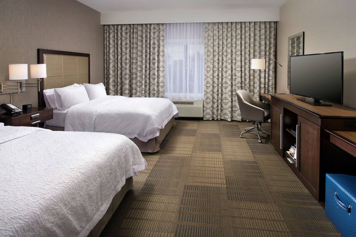 Une chambre d’hôtel avec deux lits, un bureau, une télévision et une chaise.