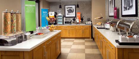 A buffet area with various food options, including a green sign that says "REFRESH PEEL SCOOP SLICE RELAX."