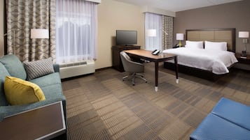 A hotel room with a bed, a desk, a chair, a television, and a lamp.