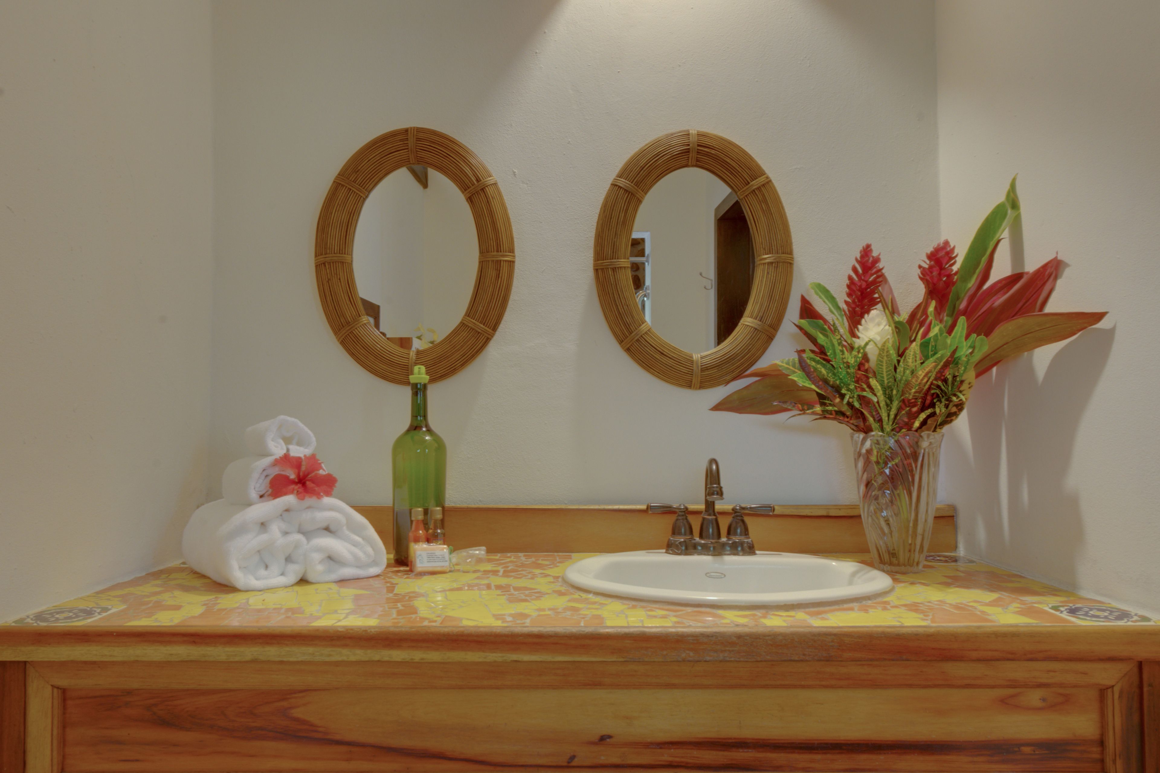 A bathroom with two round mirrors, a sink, and a vase with flowers.