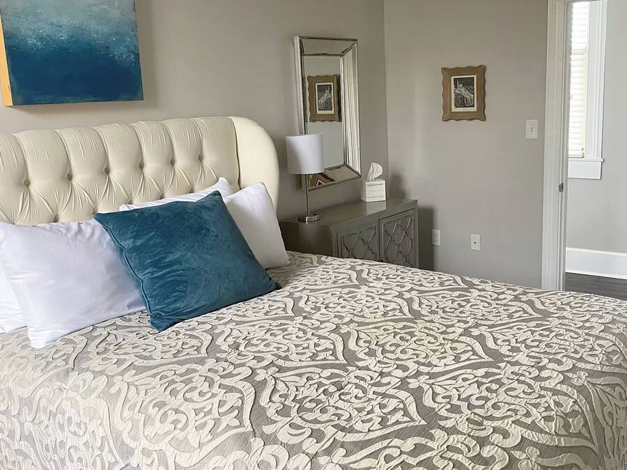 Ein Bett mit einer gepolsterten Kopfteil, einer gemusterten Tagesdecke und zwei Kissen.