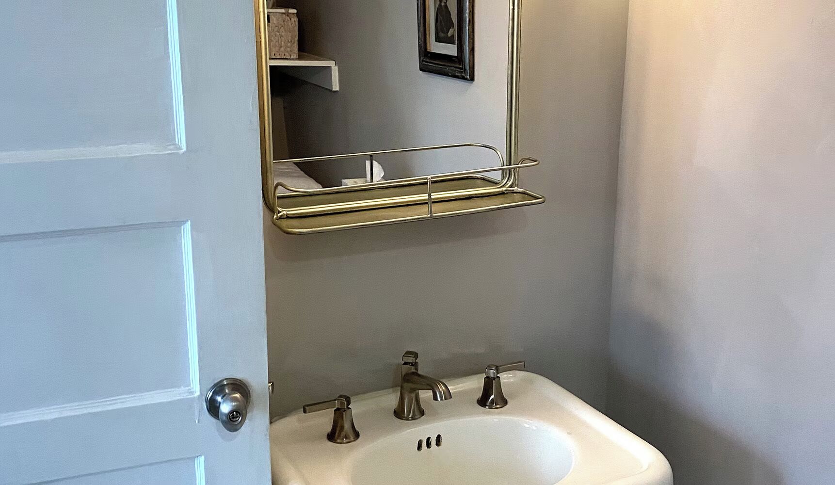 A bathroom with a white sink, two faucets, a mirror, and a towel rack.