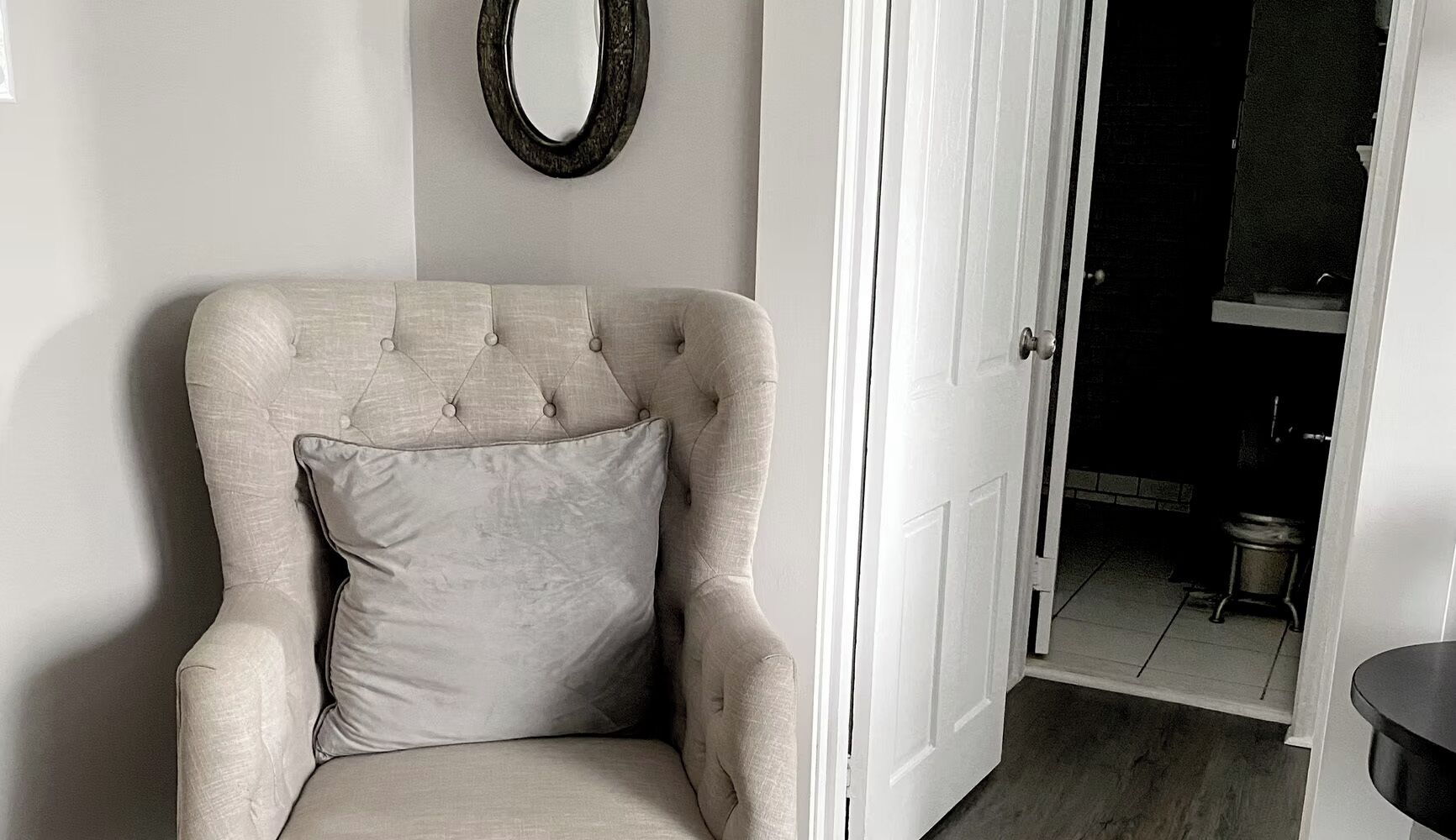 A chair with a cushion, a door, and a mirror on the wall.