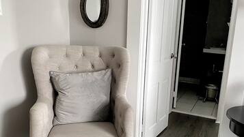 A chair with a cushion, a door, and a mirror on the wall.