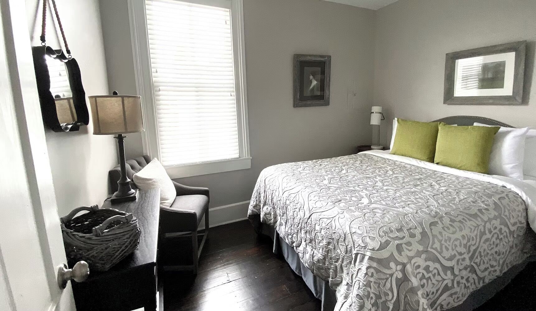 A bedroom with a bed, a chair, a lamp, a window, and a wall-mounted picture.