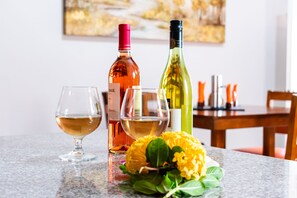 A dining table with two wine glasses, a bottle of wine, and a bunch of yellow flowers.