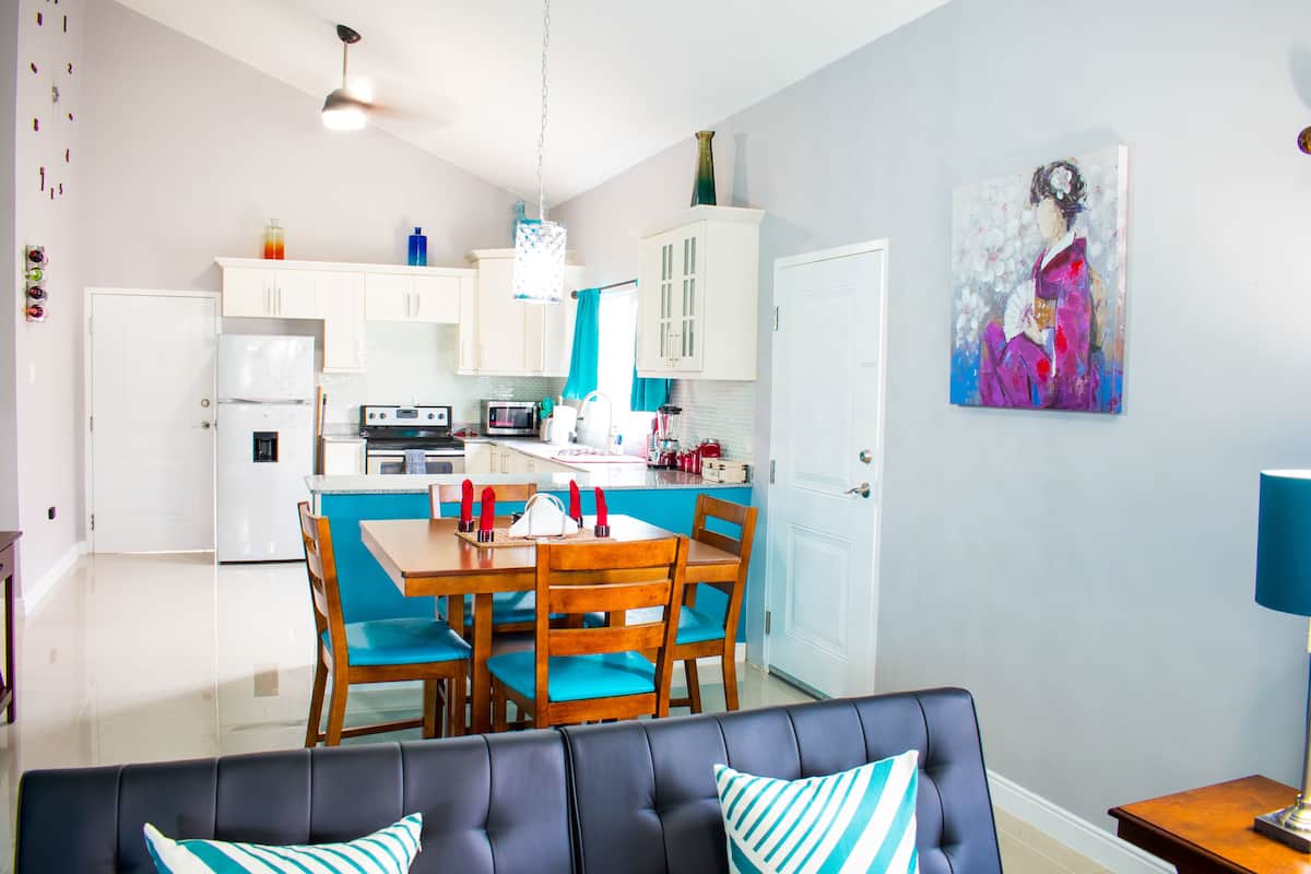 Una cucina moderna con mobili bianchi, un tavolo da pranzo con sedie e una parete decorata in blu.
