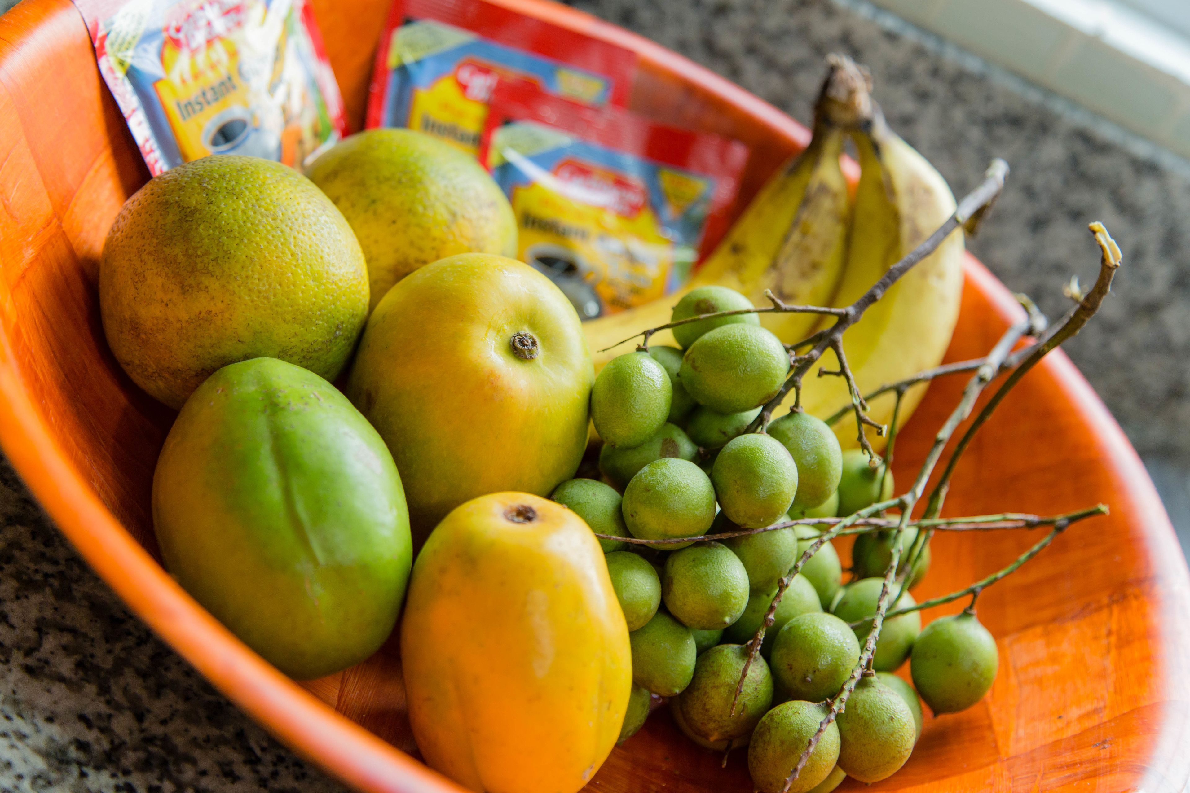 Uma tigela com várias frutas e um sachê de café instantâneo.