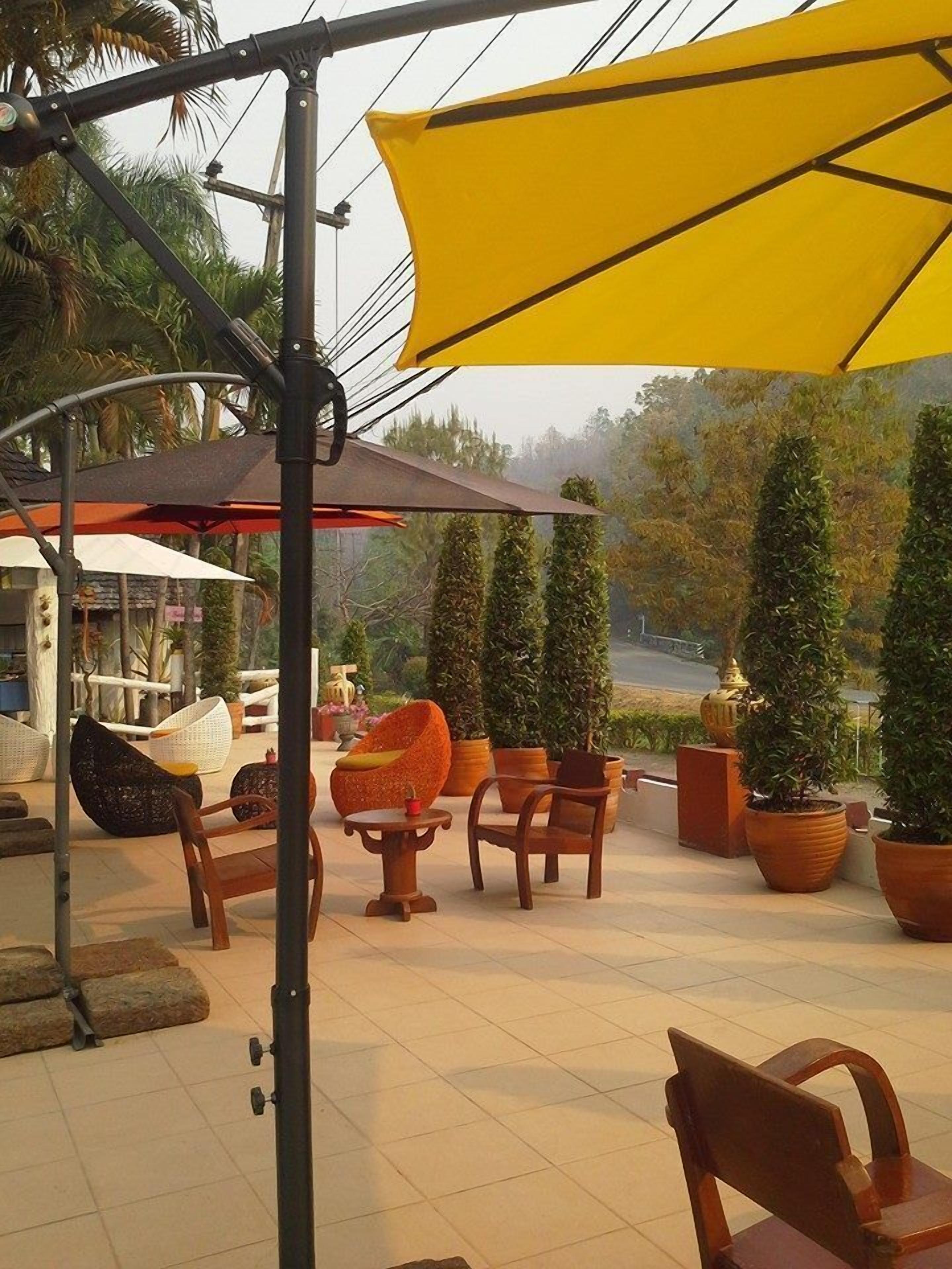 An outdoor seating area with wooden furniture and potted plants.