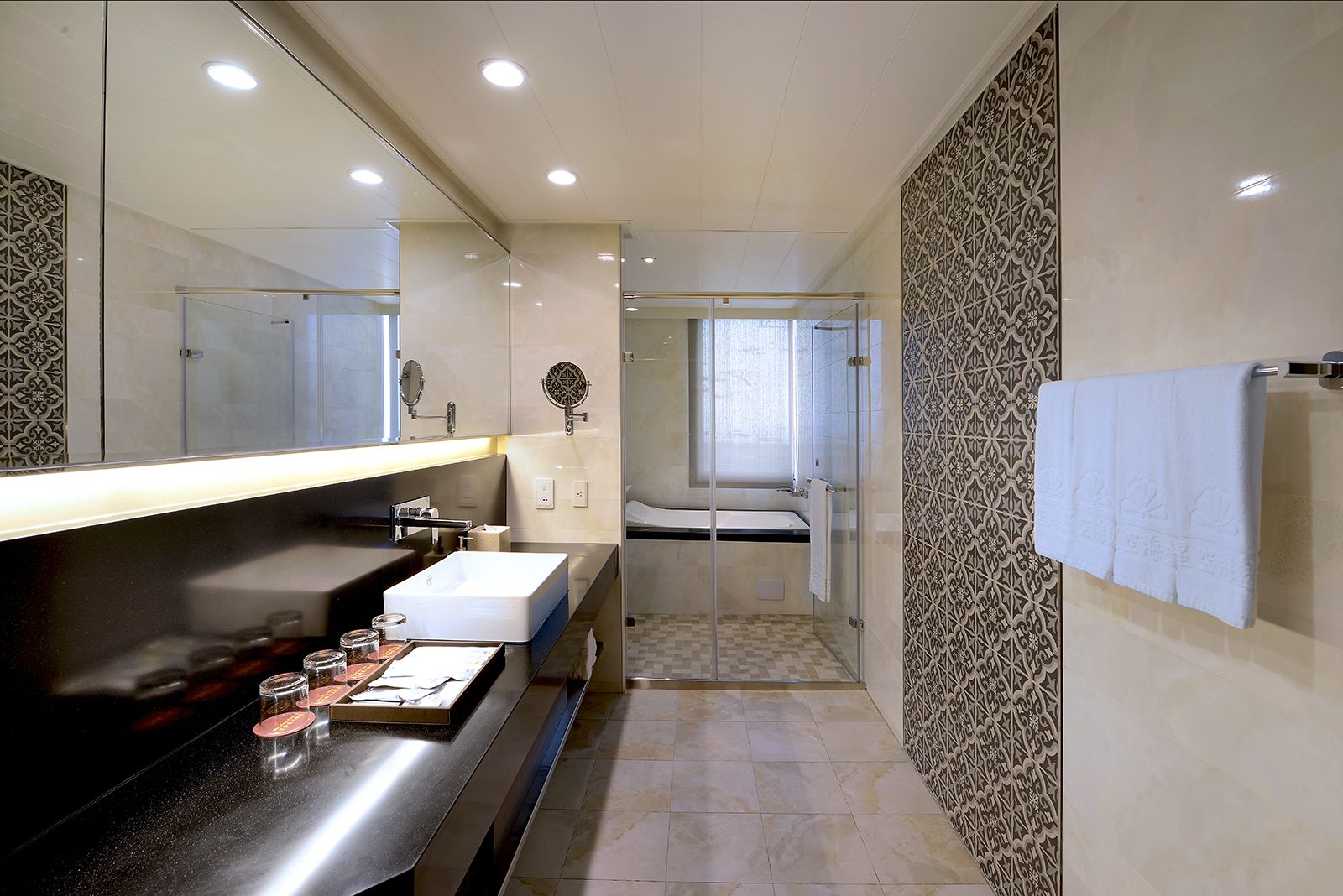 A modern bathroom with a large mirror, a white sink, and a glass-enclosed shower.