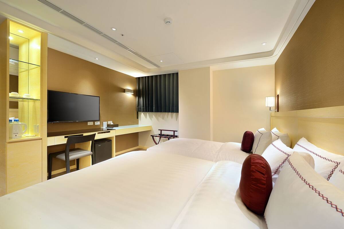 A hotel room with a bed, a desk, a television, and a minibar.