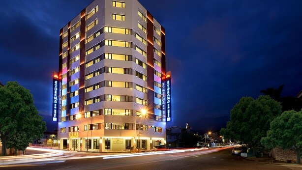 A multi-story hotel with illuminated windows and signage, a flat facade, and a street view with light trails. - Shiny Ocean Hotel (Hualien City)