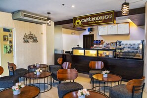 A café with a counter, menu board, and several tables and chairs.