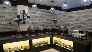 A buffet area with multiple food display cases, a life ring decoration, and hanging pendant lights. - Anchor Hotel (General Santos)