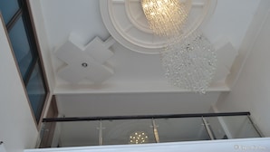 A modern interior with a circular ceiling design, a chandelier, and a glass railing. - Anchor Hotel (General Santos)