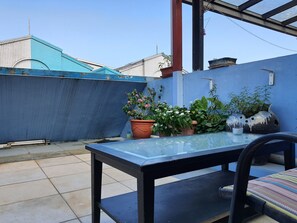 Une table à plateau en verre, entourée de chaises, de plantes en pot et d’un vase décoratif.