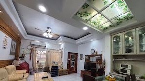 Uma sala de estar com sofá, mesa de centro, televisão e um espaço de jantar com cadeiras e mesa de vidro.
