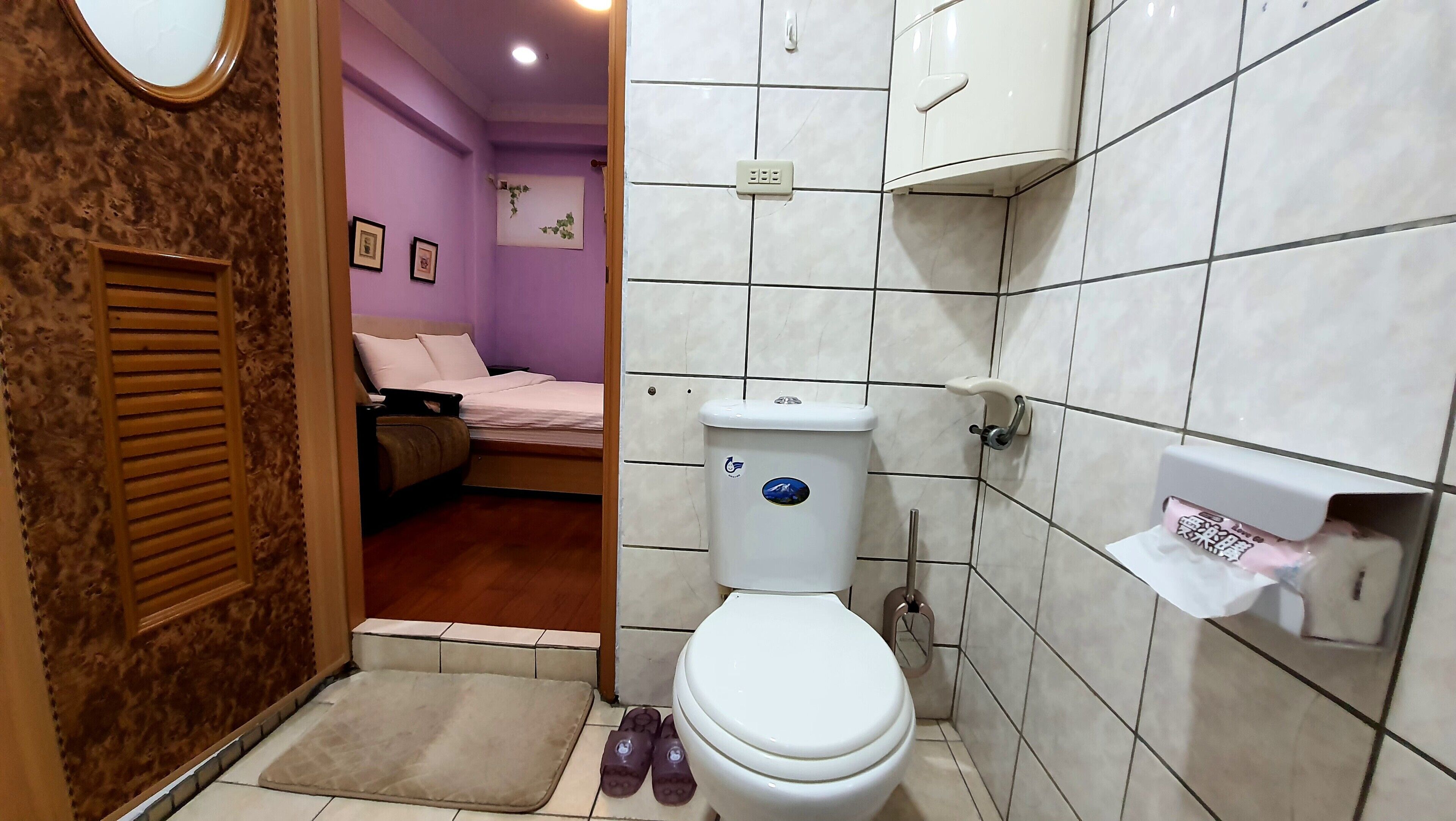 A bathroom with a toilet, a bidet, and a towel dispenser.