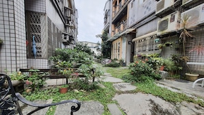 Uma passagem estreita com edifícios azulejados, plantas em vasos e um banco.
