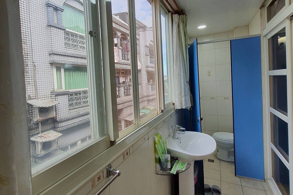 Ein Badezimmer mit Fenster, Waschbecken und Toilette.