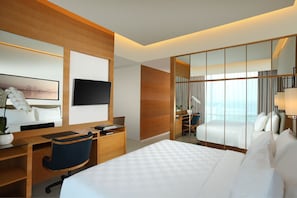 A modern hotel room with a large bed, a desk with a chair, a flat-screen TV, and a large mirror. - Resinda Hotel Karawang, Managed by Padma Hotels (Karawang)