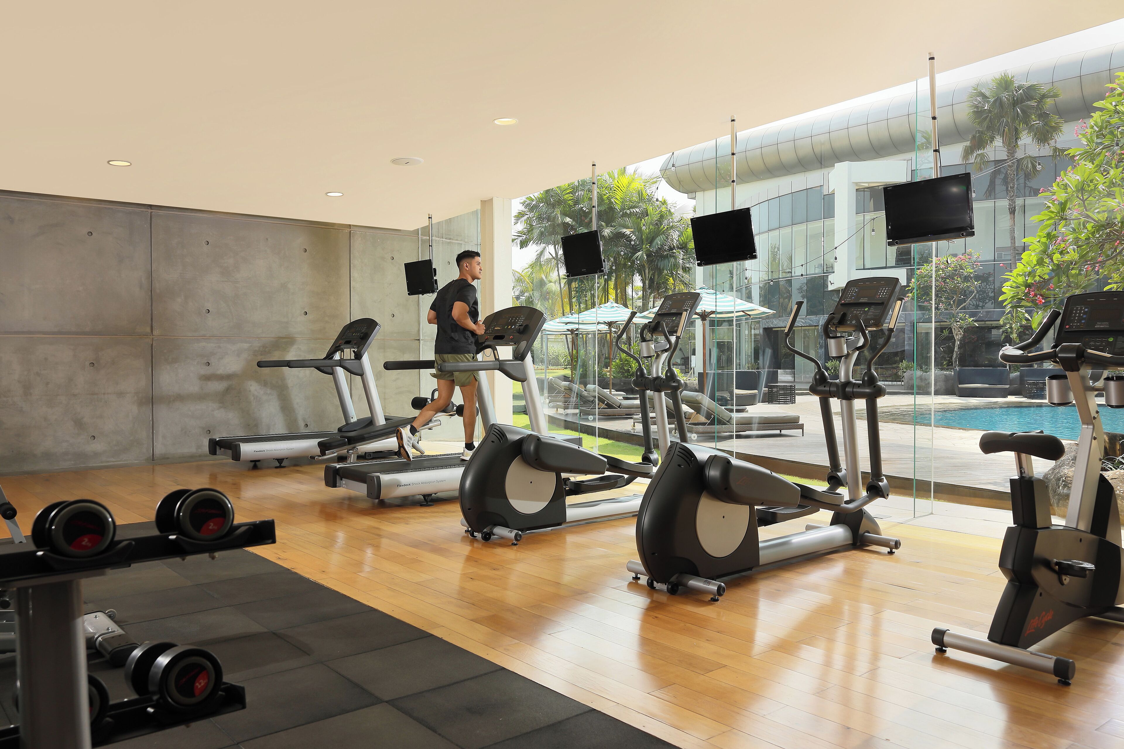 A gym with treadmills, elliptical machines, and dumbbells.