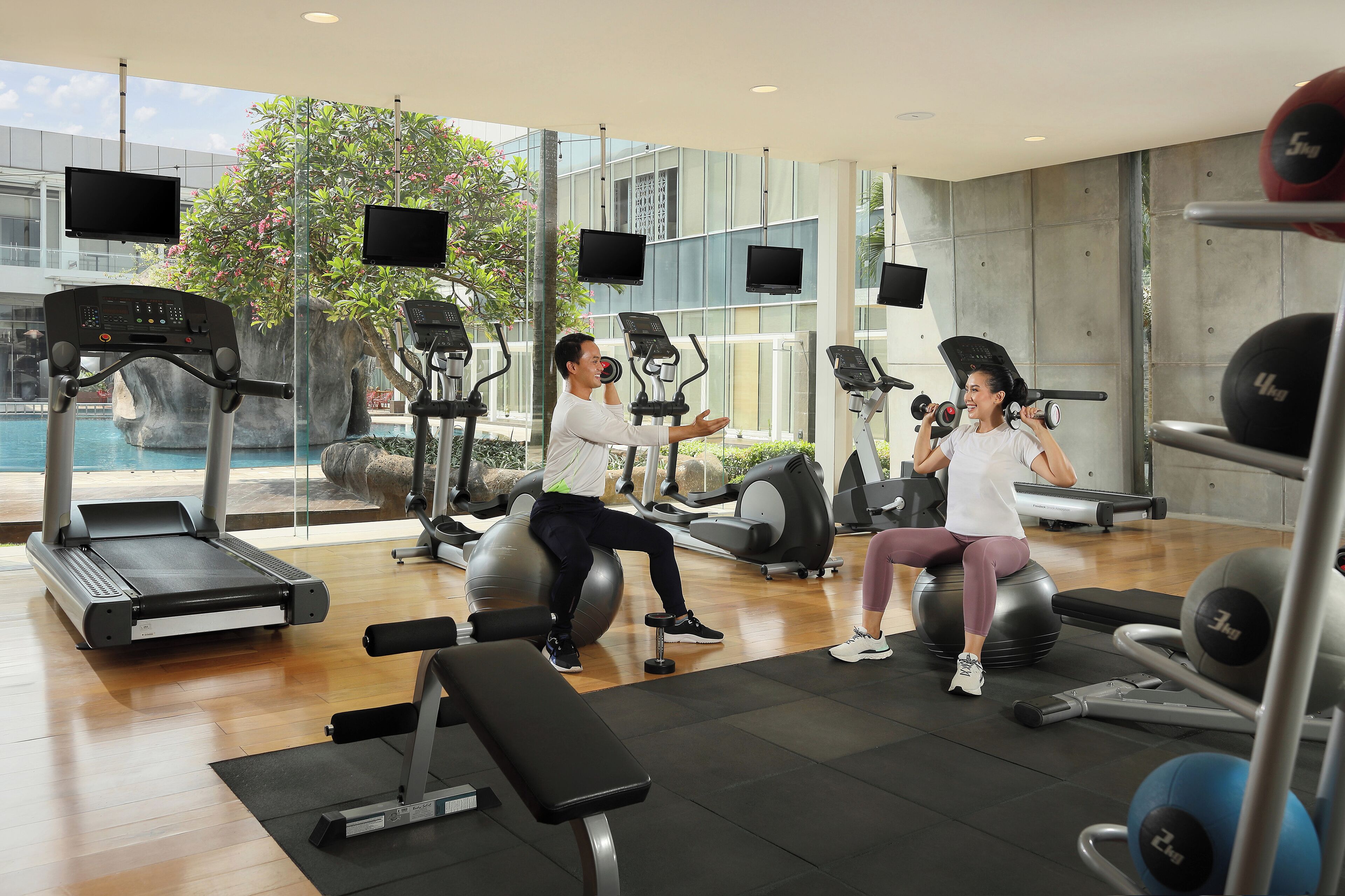 Un gimnasio moderno con cintas de correr, elípticas y pelotas de ejercicio.