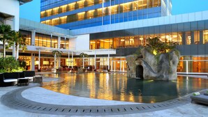 Un hôtel moderne doté d’une grande piscine extérieure, d’espaces aménagés pour se détendre et d’une façade bien éclairée.