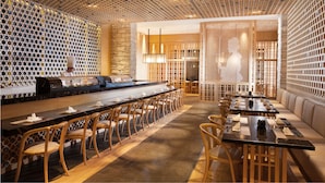 Un restaurant doté d’un long comptoir, de chaises en bois et d’un espace salon avec des tables et des coussins.