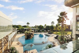 Una piscina al aire libre, sombrillas, sillones reclinables de piscina