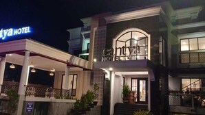 Un bâtiment à deux étages avec une enseigne indiquant « cantya HOTEL ». Il y a un espace extérieur couvert, doté de colonnes et d’un escalier menant à l’entrée.