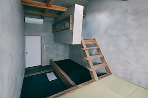 A room with a wooden ladder, a white door, and a small window.