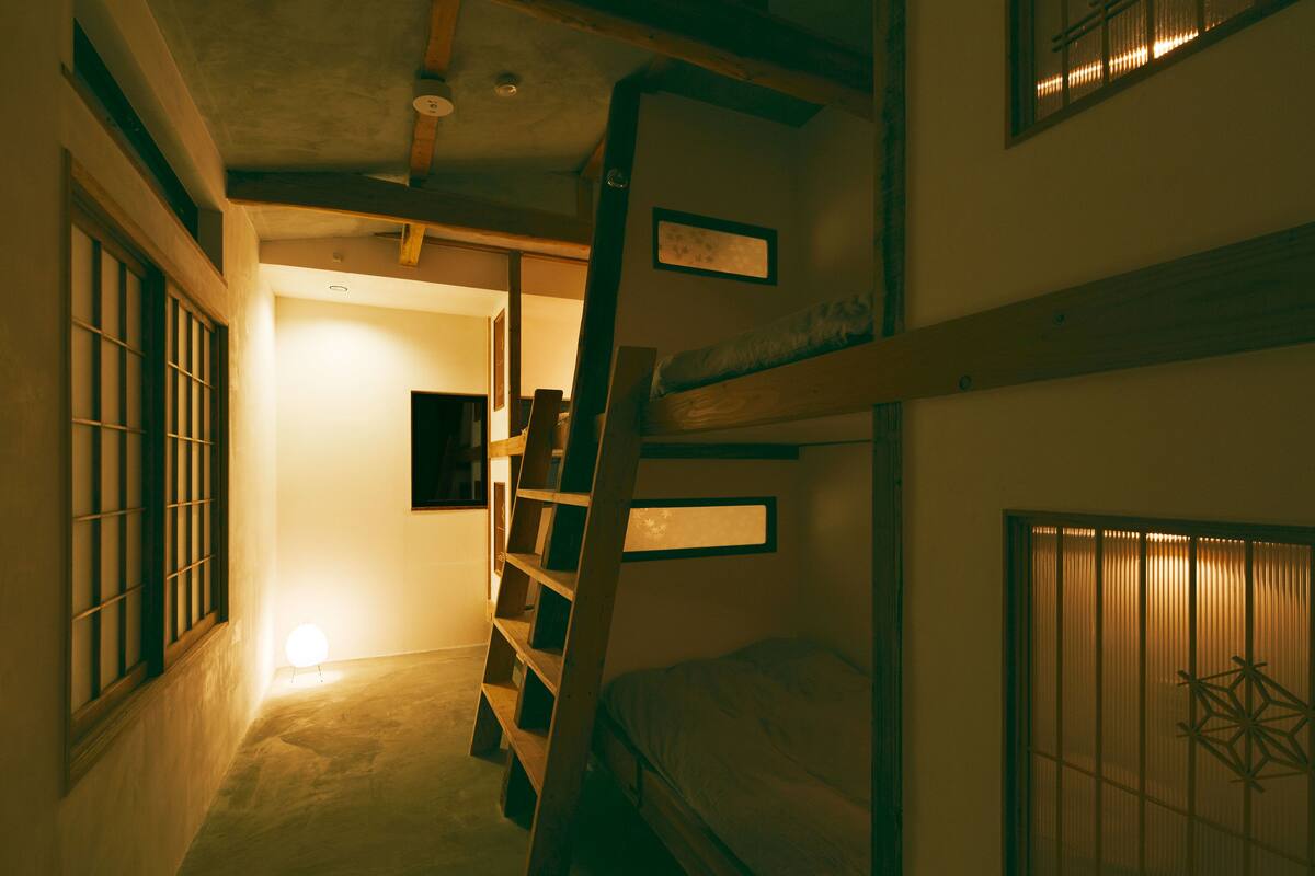 A narrow hallway with bunk beds on one side and a door leading to another room.