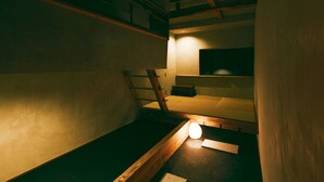 A dimly lit room with bunk beds, a ladder, and a small table with a light. - Kagelow Mt Fuji Hostel Kawaguchiko (Fujikawaguchiko)