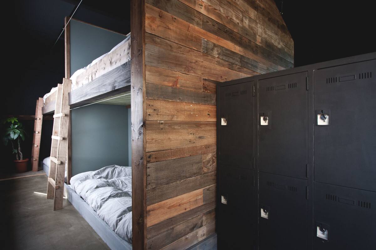 A bunk bed with a wooden headboard, a potted plant, and a set of lockers.