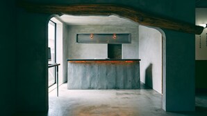 A modern kitchen with a concrete countertop, wooden beams, and a view through an archway. - Kagelow Mt Fuji Hostel Kawaguchiko (Fujikawaguchiko)