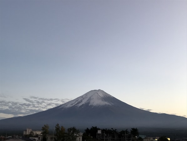 A mountain with a snow-capped peak, likely a volcano, with a clear sky above.