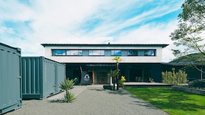 A modern two-story building with a flat roof, large windows, and a gravel driveway. - Kagelow Mt Fuji Hostel Kawaguchiko (Fujikawaguchiko)