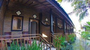 A rustic building with a wooden staircase leading to a porch, surrounded by lush greenery and a cobblestone path. - Warungku In Home Stay Senggigi (Senggigi)
