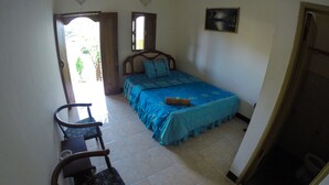 A bedroom with a bed, a chair, and a small table. There is a window and a door leading to the outside. - Warungku In Home Stay Senggigi (Senggigi)