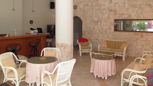 A hotel lobby with a bar, seating area, and a stone wall. - Arkadi Apartments by Checkin (Hersonissos)