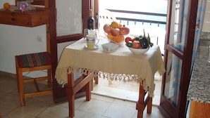 A dining area with a table set for two, a mirror, and a view through an arched doorway. - Arkadi Apartments by Checkin (Hersonissos)