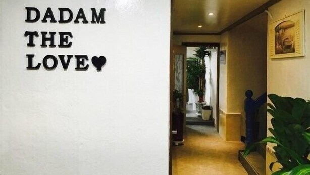 Un couloir avec une pancarte sur laquelle on peut lire « DADAM THE LOVE » et un symbole en forme de cœur.
