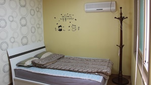 Une chambre avec un lit, un mur orné d’un motif circulaire, un mur décoré avec un chat et du texte, et un climatiseur.