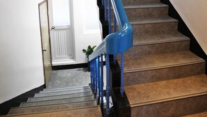 Un escalier avec une rampe bleue menant à un palier.