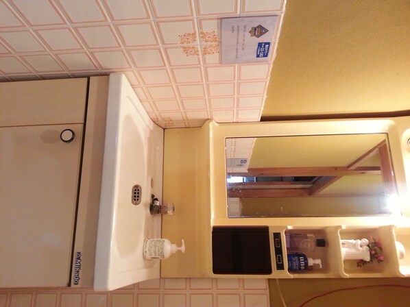 A bathroom with a sink, mirror, and toiletries. - Guest House Nakamura House (Oki)