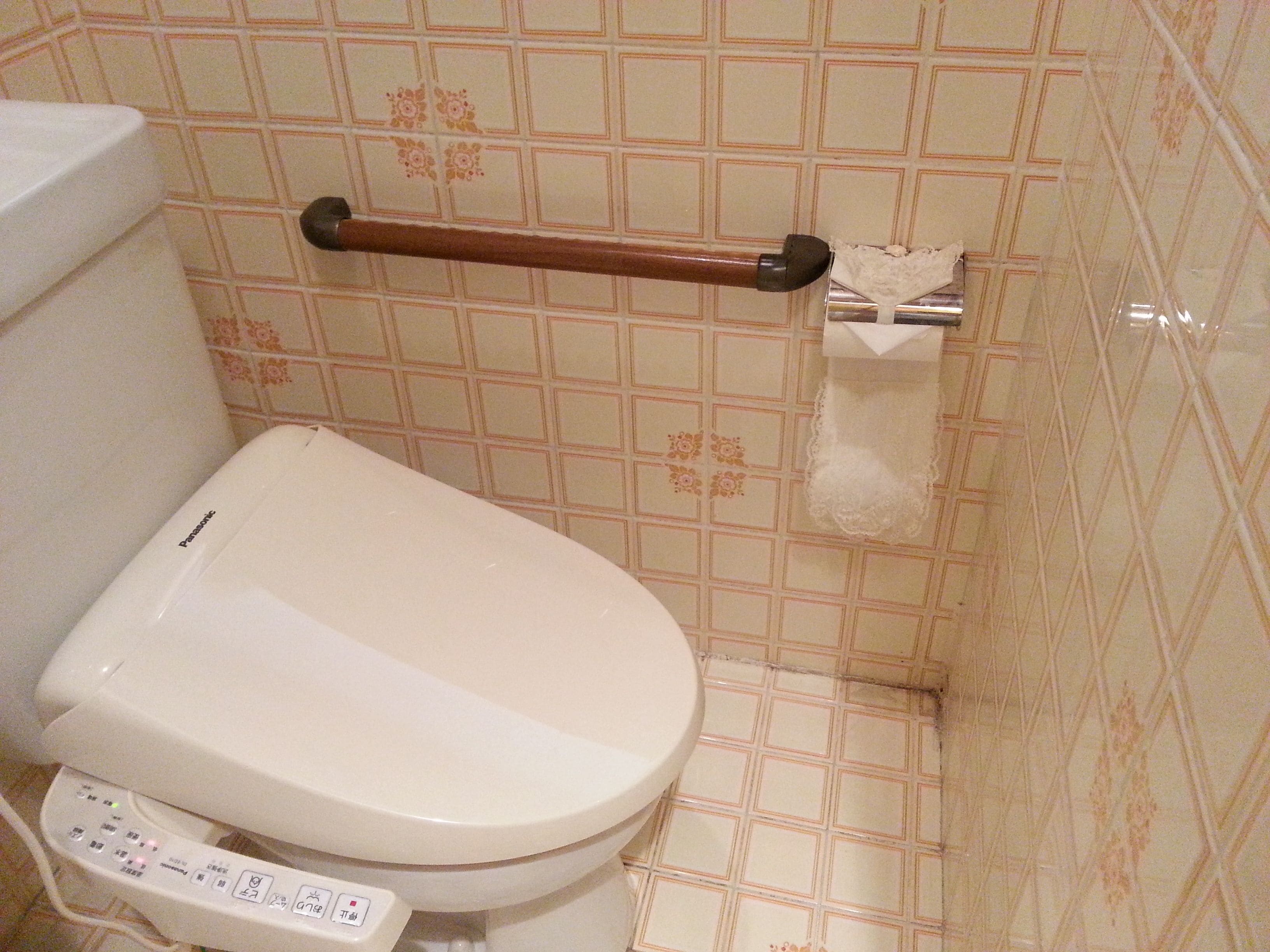 A bathroom with a toilet, a hand dryer, and a toilet paper holder.